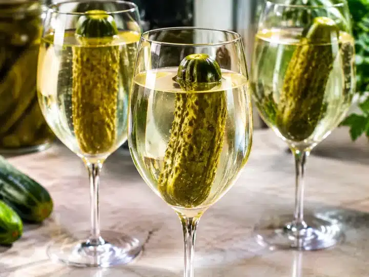 Bicchieri di vino con cetriolini verdi immersi verticalmente nel liquido