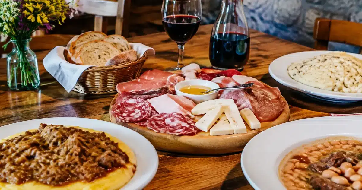 Piatti friulani tradizionali disposti su tavolo da trattoria