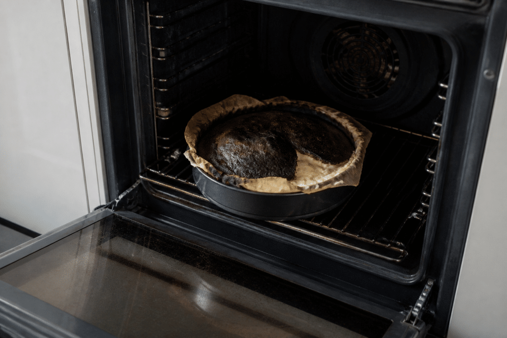 Forno aperto con dolce bruciato e impasto non cotto all'interno
