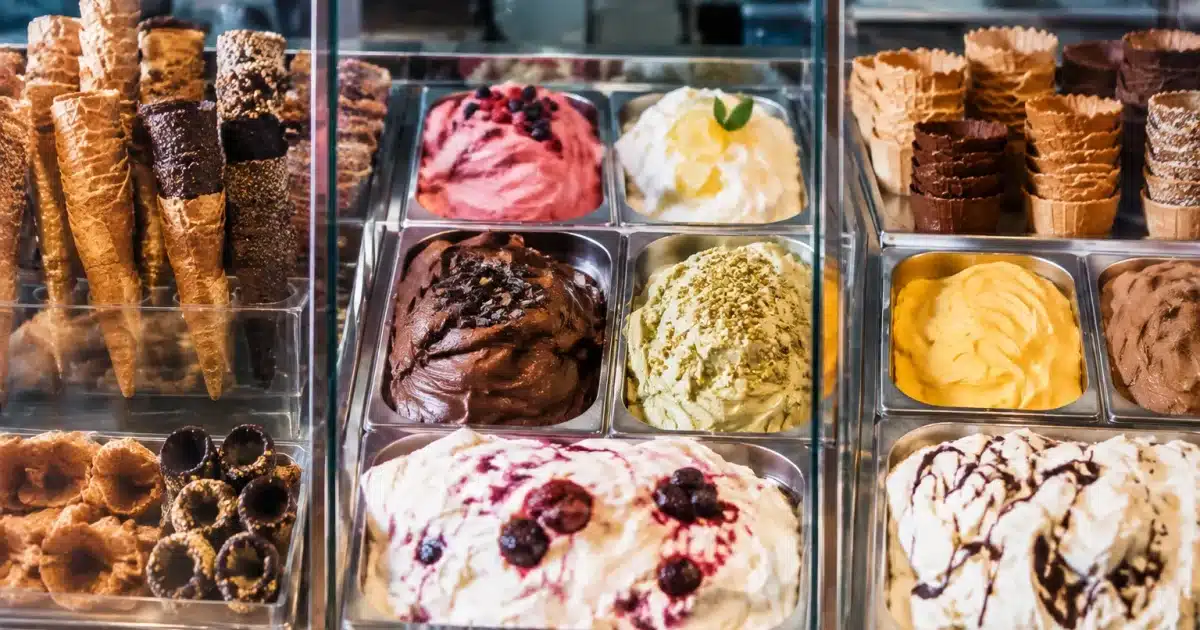 Tre vetrine di gelato artigianale con coni e coppette esposte