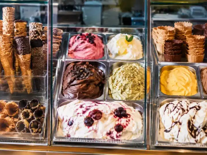 Tre vetrine di gelato artigianale con coni e coppette esposte