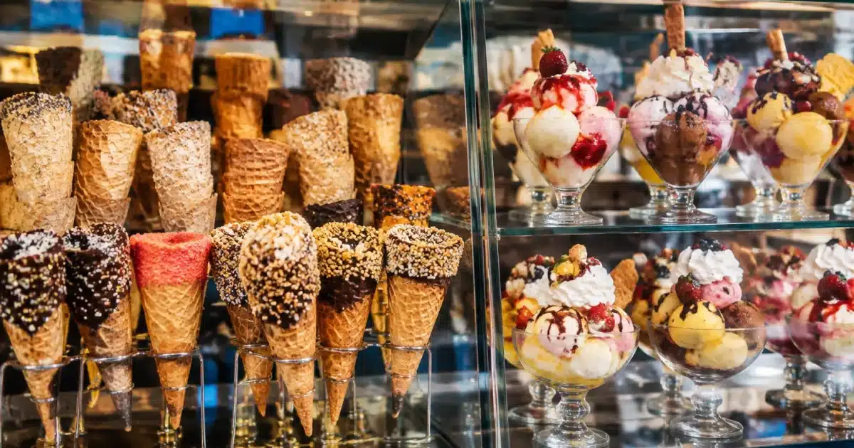Due vetrine gelato con coni e coppe colorate esposte in primo piano