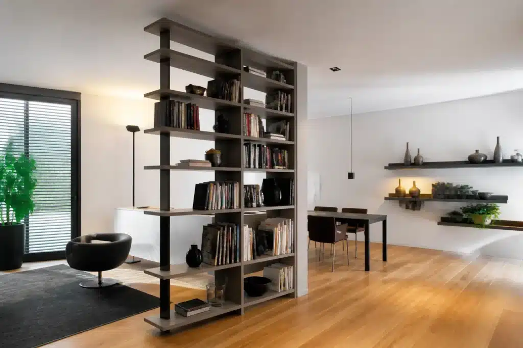 Libreria a doppia faccia e mensole sospese in spazio minimalista
