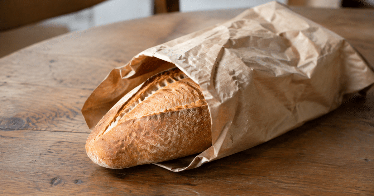 Pane fresco avvolto in carta su tavolo di legno