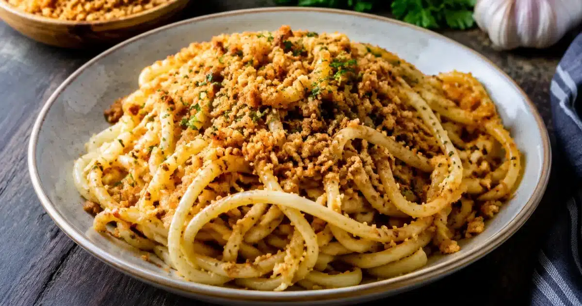 Piatto di pasta lunga ricoperto di mollica di pane tostata