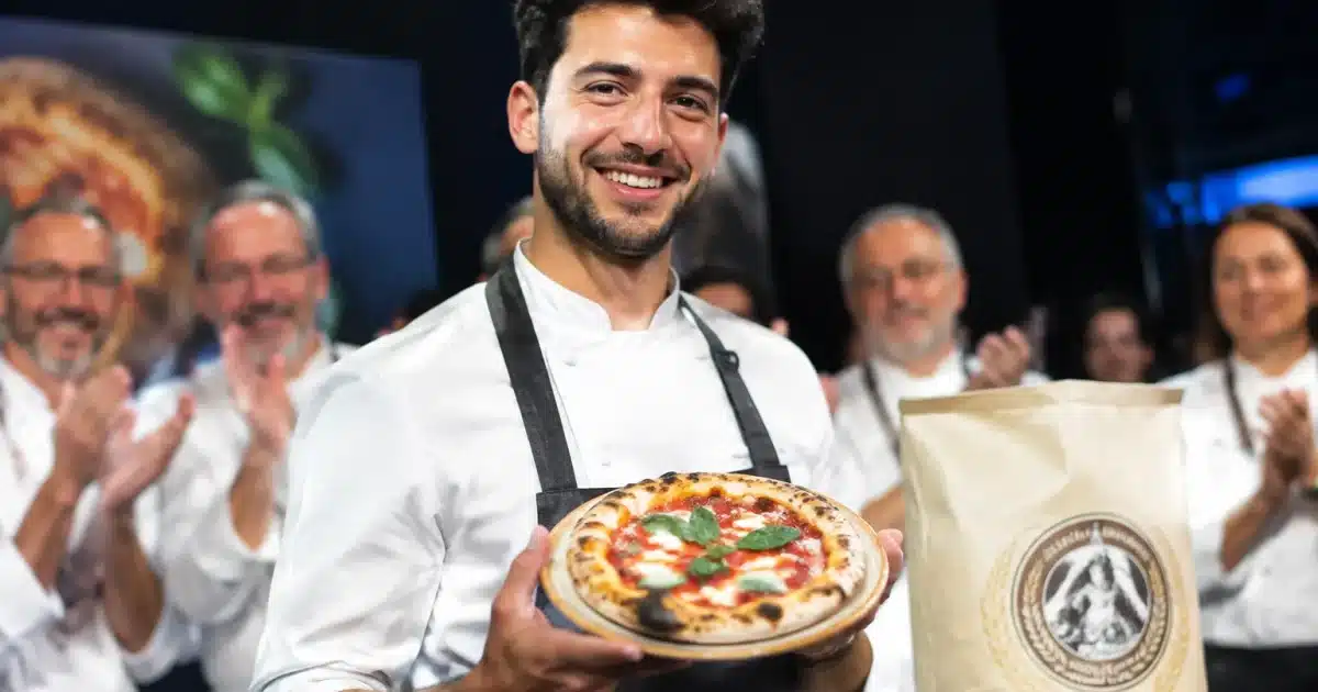 Vincitore regge pizzetta davanti giuria con premio Molino Dallagiovanna