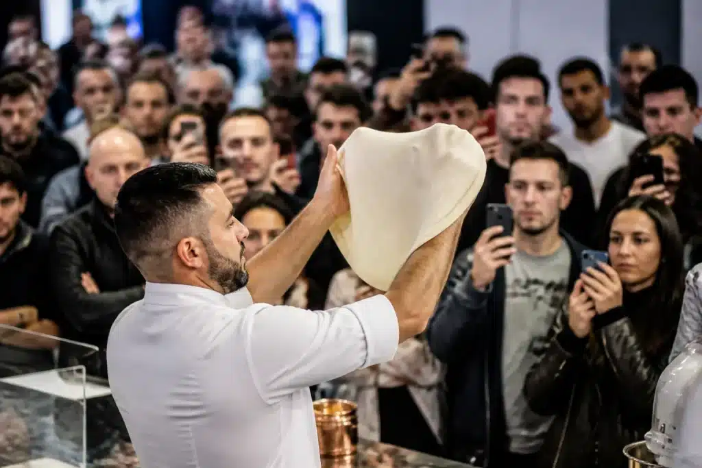 Pizzaiolo dimostra impasto davanti pubblico in fiera