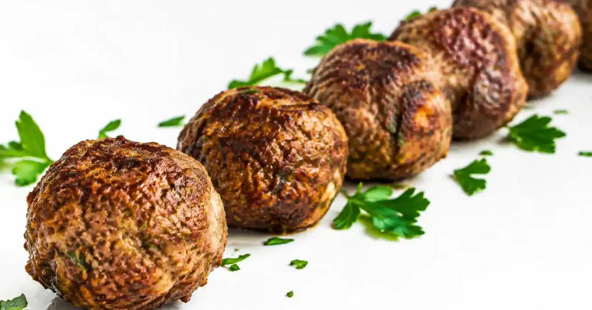 Polpette di carne macinata disposte in fila su superficie bianca