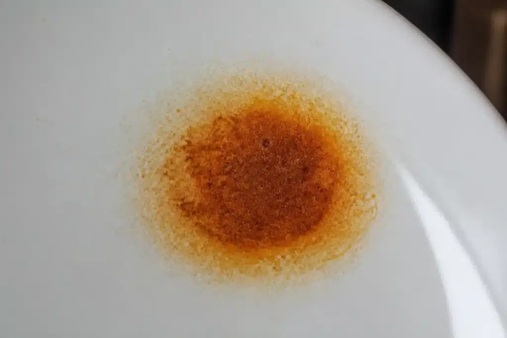 Macchia di ruggine marrone su superficie ceramica bianca